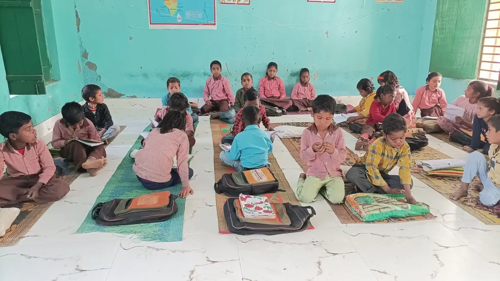 Children sitting on mats in a government primary school classroom in Uttar Pradesh