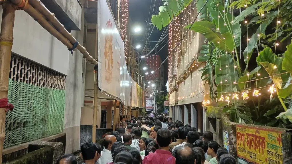 Dense crowd of visitors in a narrow lane during Durga Puja in Kolkata at night