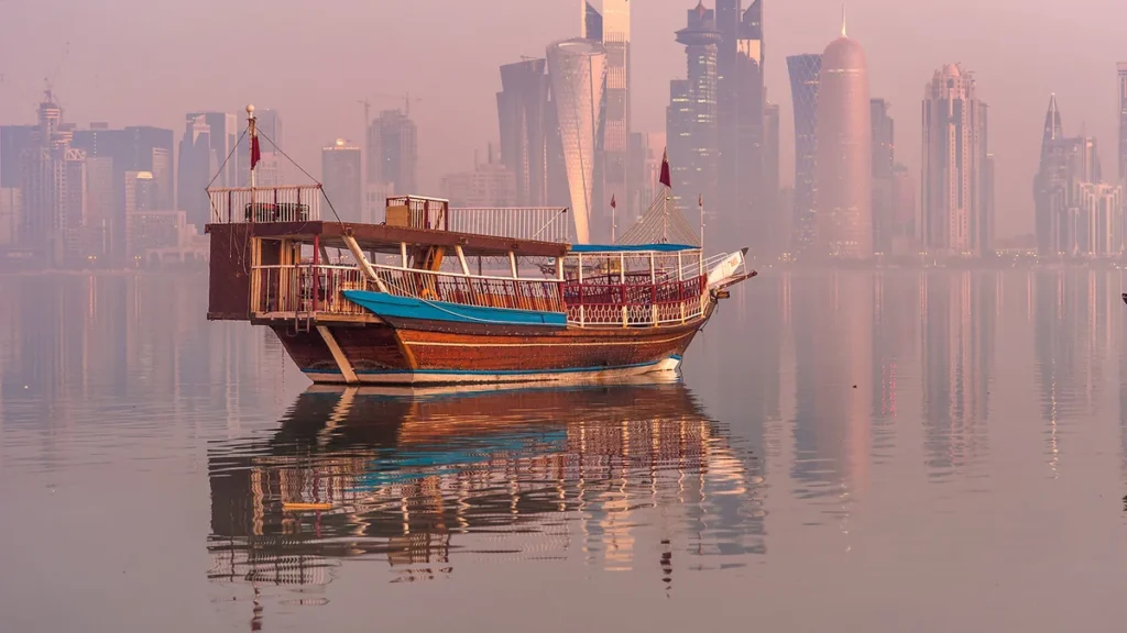 A traditional dhow on Doha Bay with the West Bay skyline of Qatar behind it