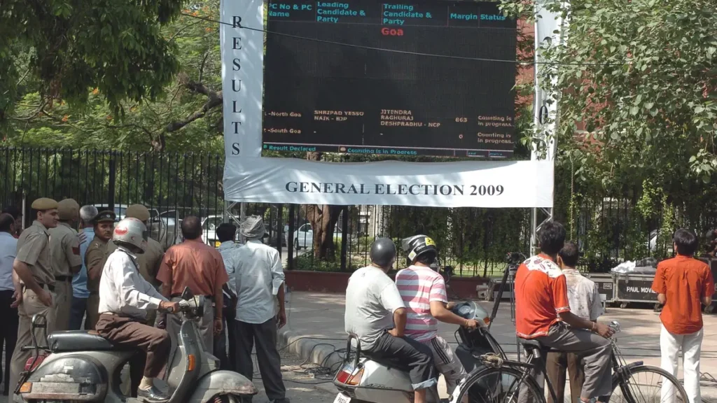 People watching the results display board outside Nirvachan Sadan, the Election Commission office in New Delhi