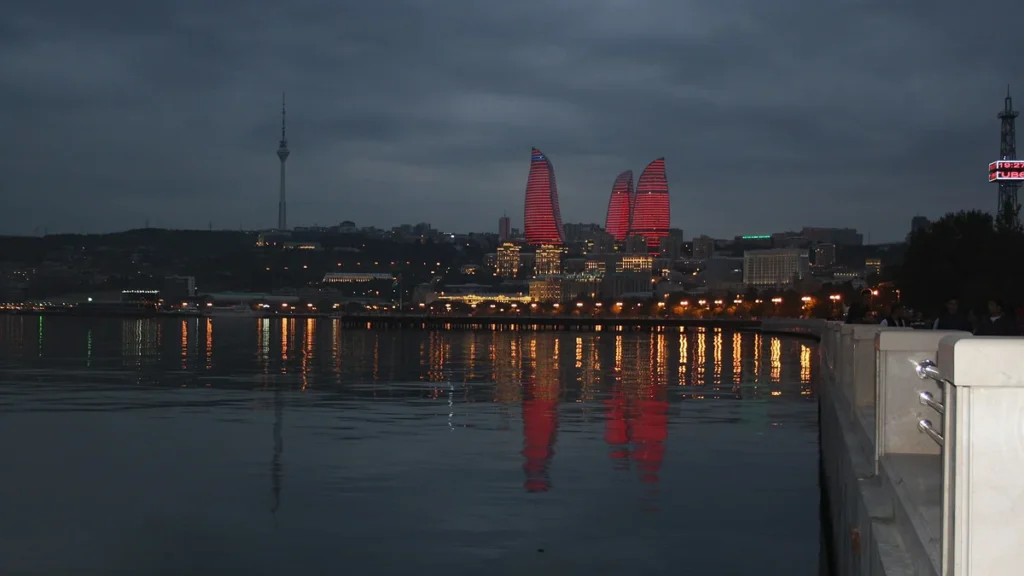 The Flame Towers lit red at dusk, seen across the water from Baku Boulevard in Azerbaijan