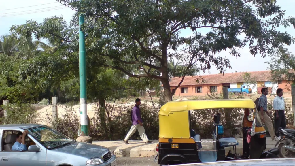 Cars and an autorickshaw with registration plates on a street in Bengaluru