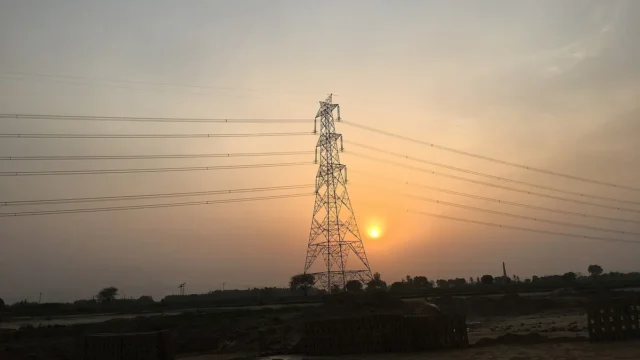 A high-voltage power transmission tower at sunset
