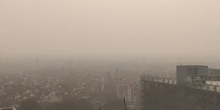Thick grey haze over the Delhi skyline in winter, buildings fading into smog